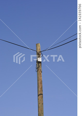 Wooden Utility Pole with Cables Against Blue Sky Wooden Utility Pole with Cables Against Blue Sky 142839766