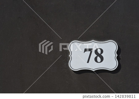 White house number plaque on a dark metal fence White house number plaque on a dark metal fence 142839811