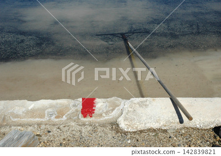 Traditional salt pan pool with wooden tool for salt harvesting Traditional salt pan pool with wooden tool for salt harvesting 142839821