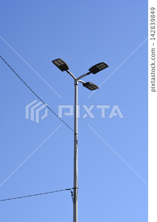 Modern LED street light post with three lamps against a clear blue sky Modern LED street light post with three lamps against a clear blue sky 142839849