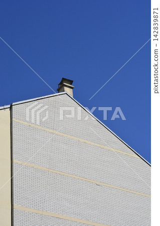 White brick facade building gable with a chimney under a blue sky White brick facade building gable with a chimney under a blue sky 142839871