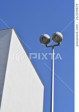 Modern LED street light post next to a white building facade Modern LED street light post next to a white building facade 142839874