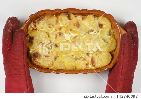 Baked potato casserole in a baking dish held with oven mitts Baked potato casserole in a baking dish held with oven mitts 142840098