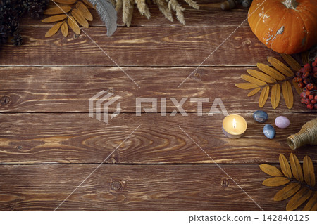 Autumn authentic layout on wooden backdrop with dry leaves, pumpkin, ashberry, agate gemstones, bottle, candle and feather, copy space, selective focus. Autumn authentic layout on wooden backdrop with dry leaves, pumpkin, ashberry, agate gemstones, bottle, candle and feather, copy space, selective focus. 142840125