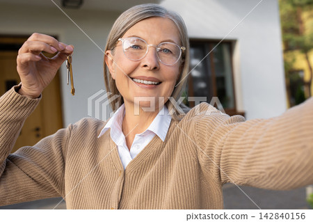Mature woman holding a key from her new home and looking excited Mature woman holding a key from her new home and looking excited 142840156