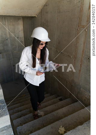 Female engineer climb steps of unfinished building Female engineer climb steps of unfinished building 142840157
