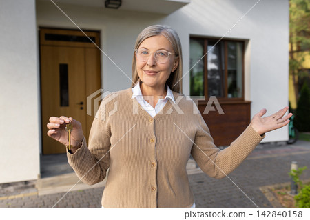 Mature woman holding a key from her new home and looking excited Mature woman holding a key from her new home and looking excited 142840158