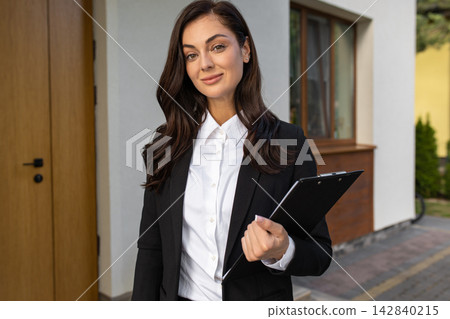 Good-looking elegant young woman at the door of a new house Good-looking elegant young woman at the door of a new house 142840215