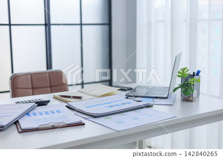 Modern white office workspace of financial or accounting tasks, featuring a laptop, a tablet, financial charts, reports, a calculator, and a notebook on a white desk. Modern white office workspace of financial or accounting tasks, featuring a laptop, a tablet, financial charts, reports, a calculator, and a notebook on a white desk. 142840265