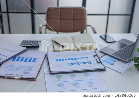 Modern white office workspace of financial or accounting tasks, featuring a laptop, a tablet, financial charts, reports, a calculator, and a notebook on a white desk. Modern white office workspace of financial or accounting tasks, featuring a laptop, a tablet, financial charts, reports, a calculator, and a notebook on a white desk. 142840266