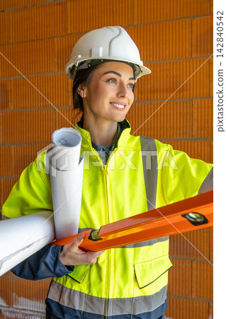 Close up of smiling female architect holding building tools Close up of smiling female architect holding building tools 142840542