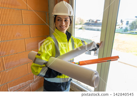 Happy female architect holding rolled blueprints Happy female architect holding rolled blueprints 142840545