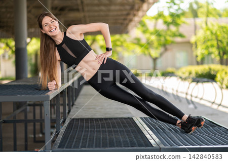 Slim fit young woman exercising in the open air and looking focused Slim fit young woman exercising in the open air and looking focused 142840583