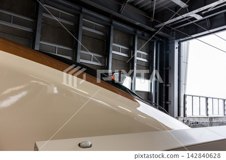 A low-angle shot of the lead car of a Hokuriku Shinkansen train stopped at Tsuruga Station platform during a snowfall. A low-angle shot of the lead car of a Hokuriku Shinkansen train stopped at Tsuruga Station platform during a snowfall. 142840628