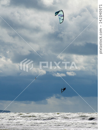 Kitesurfer Flying High Above Rough Baltic Sea Waves Under Dramatic Storm Clouds on Windy Day 142840971