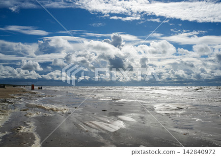Dramatic Cloudscape Over Windswept Baltic Sea and Wet Sandy Beach with Sunlit Waves on the Coast Dramatic Cloudscape Over Windswept Baltic Sea and Wet Sandy Beach with Sunlit Waves on the Coast 142840972