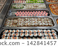 Sushi roll japanese food in grocery store, buffet, or food court. Buying sushi rolls in a store. Japanese food. Various types of sushi rolls on display at a grocery store. 142841457