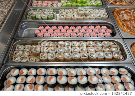 Sushi roll japanese food in grocery store, buffet, or food court. Buying sushi rolls in a store. Japanese food. Various types of sushi rolls on display at a grocery store. Sushi roll japanese food in grocery store, buffet, or food court. Buying sushi rolls in a store. Japanese food. Various types of sushi rolls on display at a grocery store. 142841457