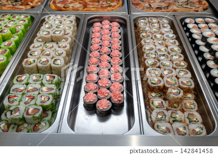 Sushi roll japanese food in grocery store, buffet, or food court. Buying sushi rolls in a store. Japanese food. Various types of sushi rolls on display at a grocery store. Sushi roll japanese food in grocery store, buffet, or food court. Buying sushi rolls in a store. Japanese food. Various types of sushi rolls on display at a grocery store. 142841458