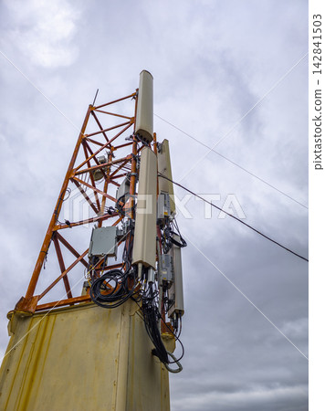 Telecommunications Tower with Antennas Against Cloudy Sky Telecommunications Tower with Antennas Against Cloudy Sky 142841503