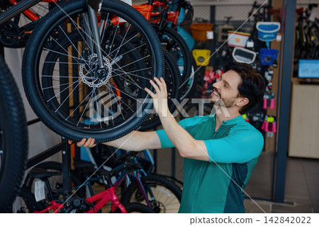 Mechanic fixing wheel amidst vibrant bikes Mechanic fixing wheel amidst vibrant bikes 142842022