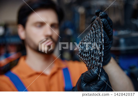 Technician carefully inspects and cleans bicycle sprockets professionally Technician carefully inspects and cleans bicycle sprockets professionally 142842037