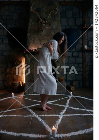 Mystical woman stands unshod inside chalk encirclement engaging in sacred symbolic movements 142842064