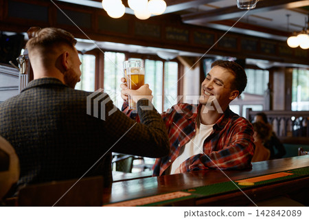 Two caucasian men share relaxed moments and cheerful conversations at friendly pub Two caucasian men share relaxed moments and cheerful conversations at friendly pub 142842089