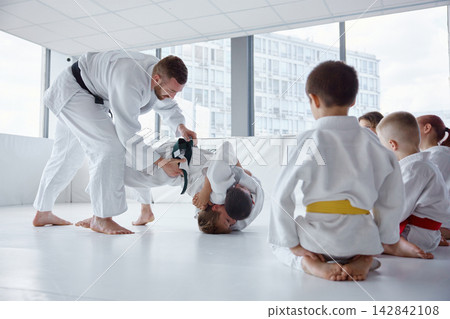 Sensei adjusting student grip during drill to improve technique and safety Sensei adjusting student grip during drill to improve technique and safety 142842108