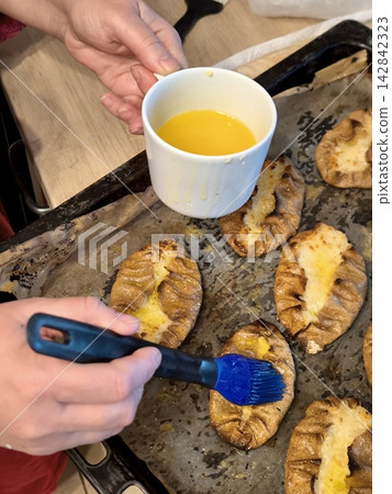 Brushing hot Karelian pasties with melted butter. Brushing hot Karelian pasties with melted butter. 142842323