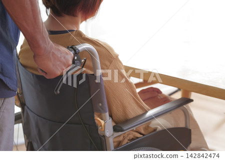 丈夫攙扶著坐輪椅的妻子。 丈夫攙扶著坐輪椅的妻子。 142842474