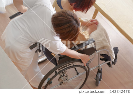 護理人員正在協助一位坐在輪椅上的女士 護理人員正在協助一位坐在輪椅上的女士 142842478