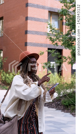 A woman uses a city map and geolocation on her smartphone to navigate the area while traveling. 142843132