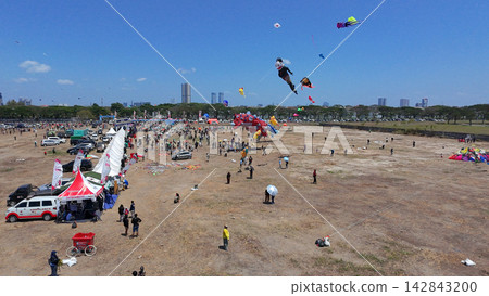 Annual Surabaya kite festival featuring giant colorful kites flying over open field under clear blue sky. Annual Surabaya kite festival featuring giant colorful kites flying over open field under clear blue sky. 142843200