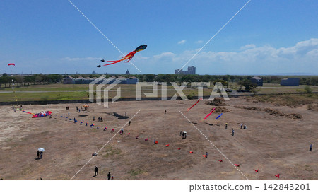 Annual Surabaya kite festival featuring giant colorful kites flying over open field under clear blue sky. Annual Surabaya kite festival featuring giant colorful kites flying over open field under clear blue sky. 142843201