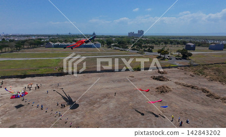 Annual Surabaya kite festival featuring giant colorful kites flying over open field under clear blue sky. Annual Surabaya kite festival featuring giant colorful kites flying over open field under clear blue sky. 142843202