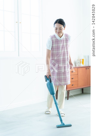 一名從事家事清潔工作的女子正在吸塵。 一名從事家事清潔工作的女子正在吸塵。 142843829