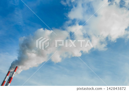 Environmental pollution, environmental problem, smoke from the chimney of a industrial plant or thermal power plant against the blue sky Environmental pollution, environmental problem, smoke from the chimney of a industrial plant or thermal power plant against the blue sky 142843872