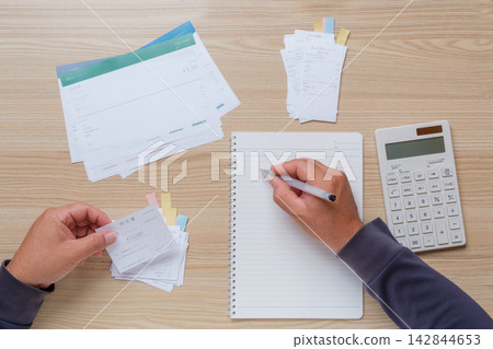 I'm organizing receipts and utility bills and recording them in a notebook as I prepare for filing my tax return. I'm organizing receipts and utility bills and recording them in a notebook as I prepare for filing my tax return. 142844653