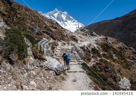 Rear view of tourist trekking in Sagarmatha national park, Nepal with beautiful view of Mt.lhotse (8,516 m) in the background. 142845418