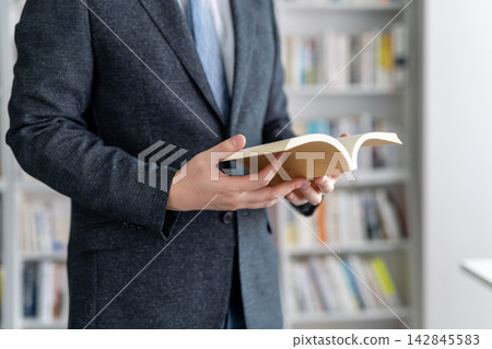 一位身穿西裝的商人正在書房看書。 142845583