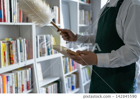 一名男書店員工正在清理書架。 一名男書店員工正在清理書架。 142845590