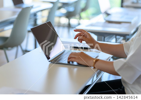 A woman working at her desk using a laptop. A woman working at her desk using a laptop. 142845614