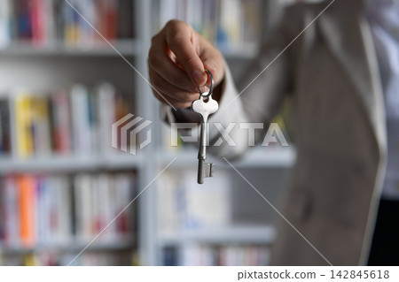 A business person's hand offering a key. 142845618
