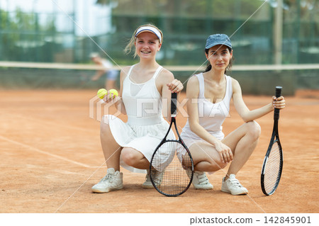 Two young women in sportswear against backdrop of outdoor tennis court Two young women in sportswear against backdrop of outdoor tennis court 142845901