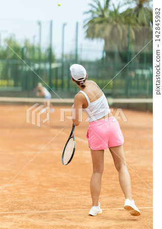 Female athlete plays tennis on open court Female athlete plays tennis on open court 142845982