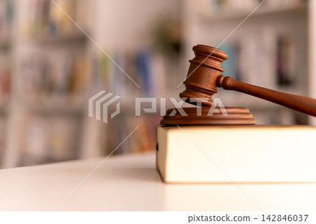 律師辦公室的桌子上放著一把木槌和一些法律教科書。 律師辦公室的桌子上放著一把木槌和一些法律教科書。 142846037