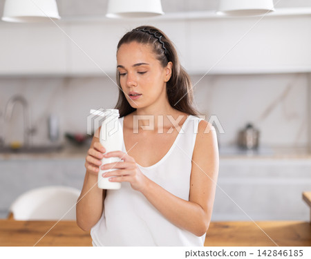 Pleased young girl drinking bottled kefir in kitchen Pleased young girl drinking bottled kefir in kitchen 142846185