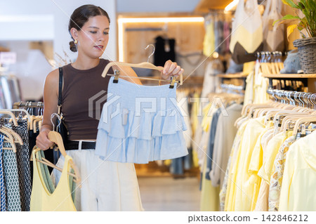 Young woman choosing a set of clothes for the summer Young woman choosing a set of clothes for the summer 142846212