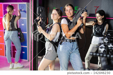 Two woman in the special vests holding laser guns and playing laser tag with girlfriends on bachelorette Two woman in the special vests holding laser guns and playing laser tag with girlfriends on bachelorette 142846230